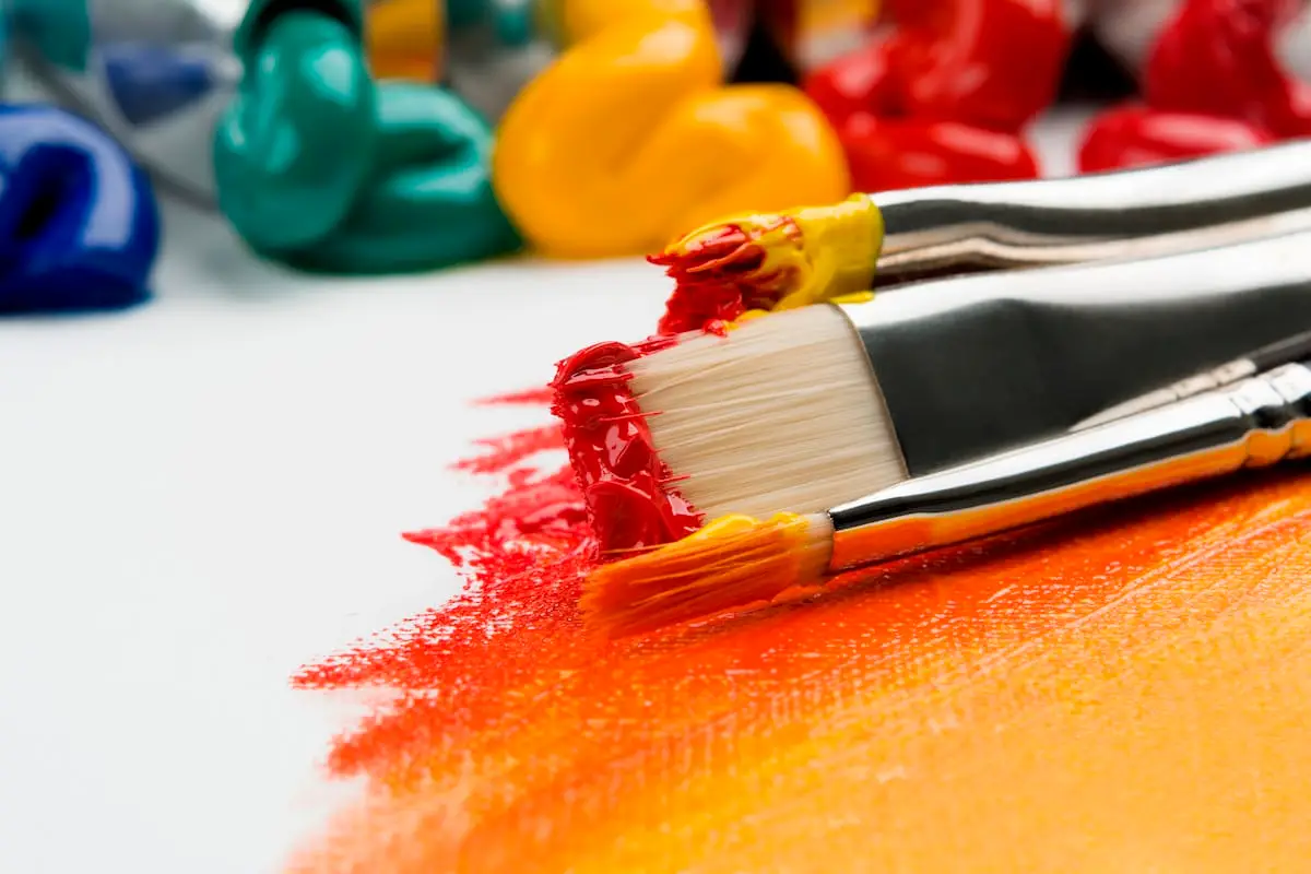 Paintbrush applying red colour to a canvas